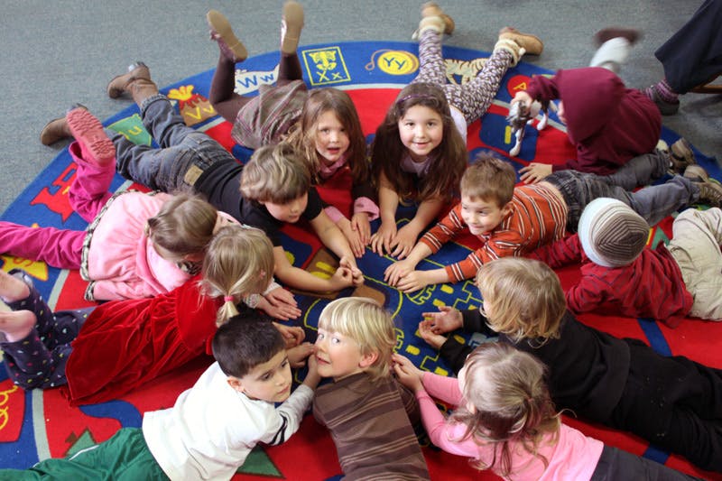 Group of children lying in a circle on a colorful rug