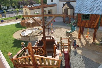 Playground with a wooden ship structure and a treehouse with a slide
