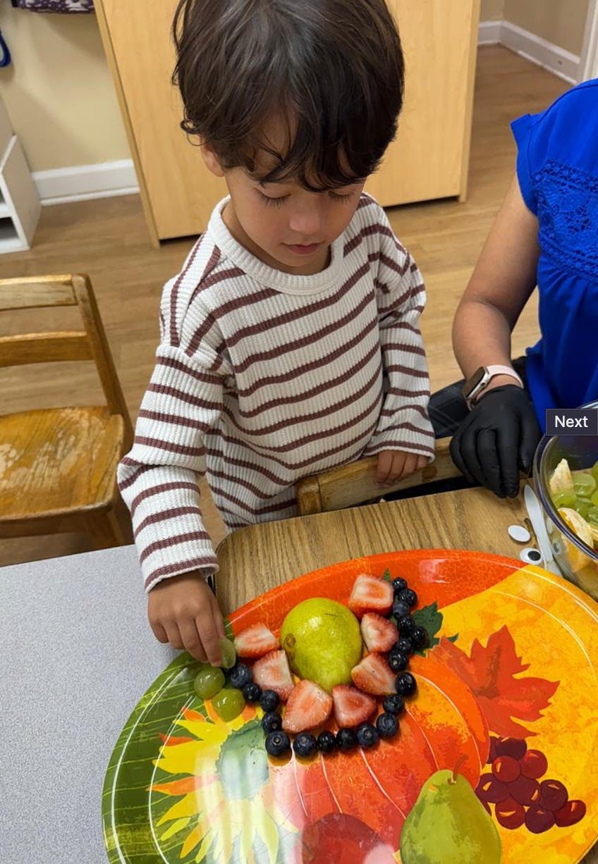Child arranging fruit on a decorative plate