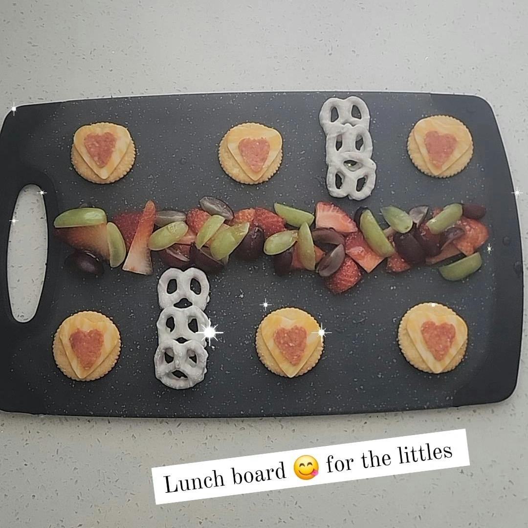 Snack board with fruit, crackers with heart shapes, and pretzels