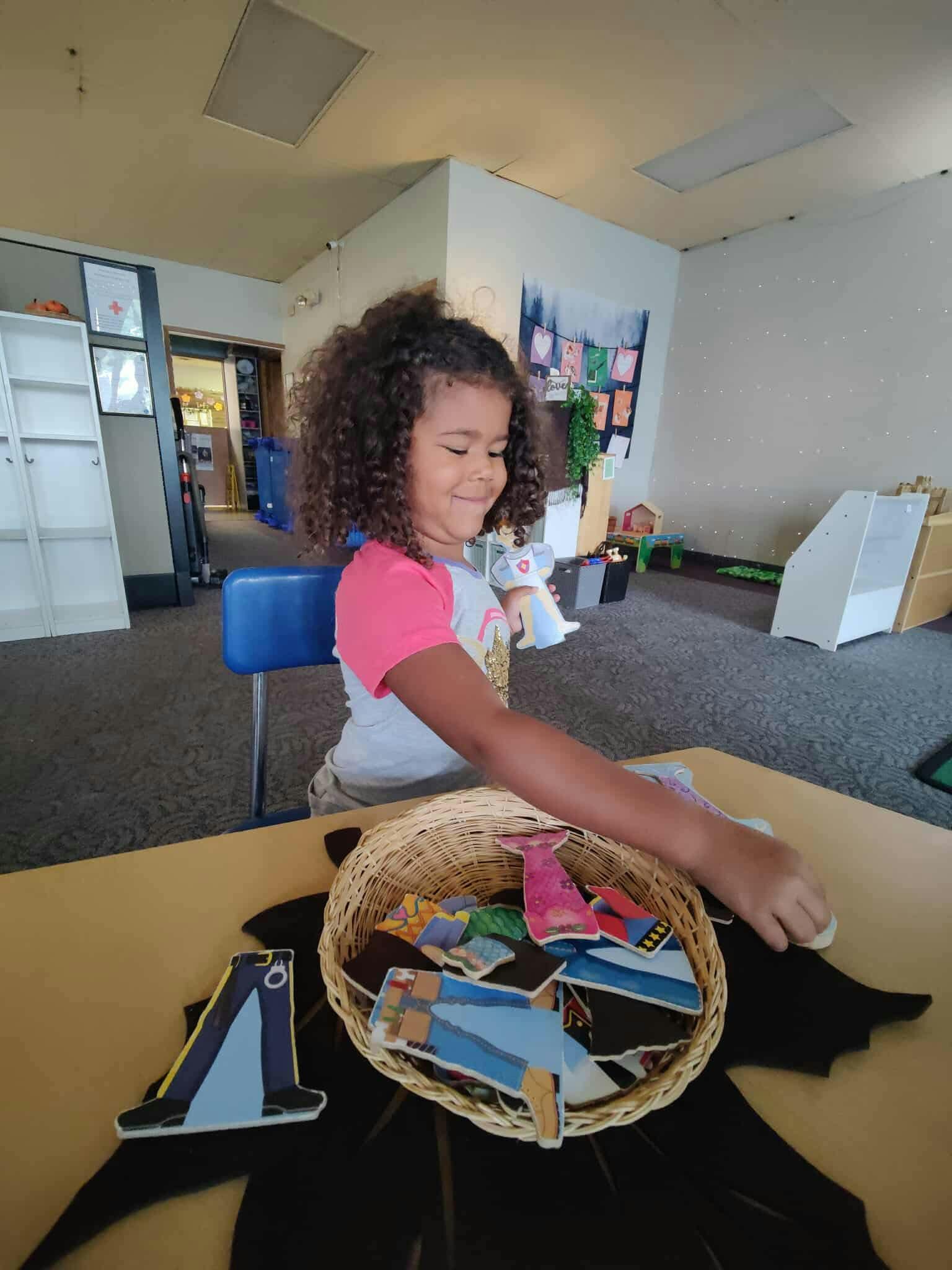 Child playing with felt cutouts at a table in a classroom