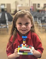 Child holding up a colorful Lego creation
