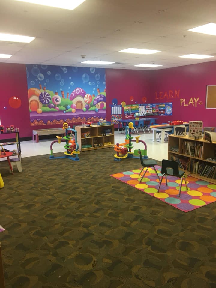 Children's play area with toys, tables, and a colorful mural
