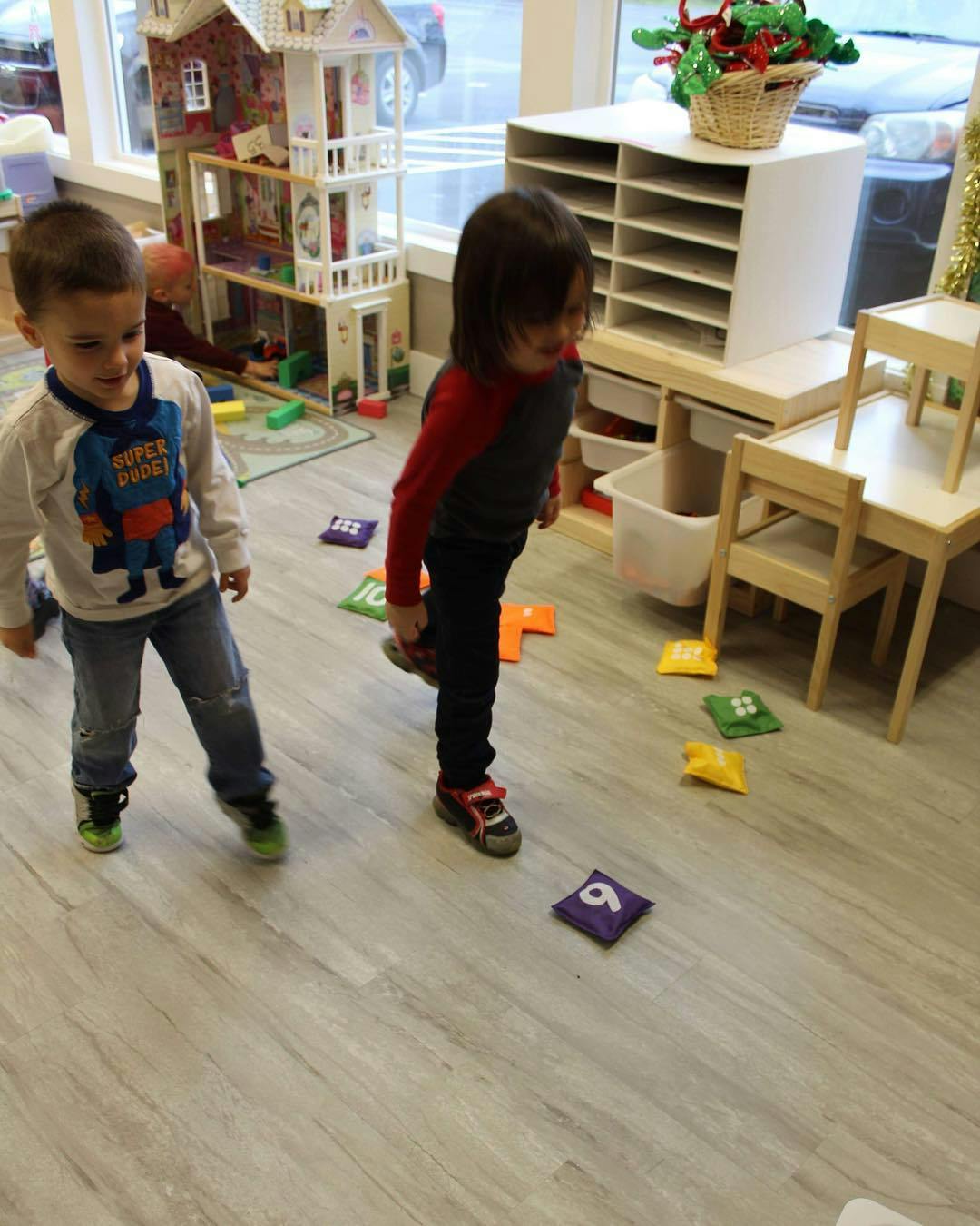 Two children standing on a wooden floor with colorful beanbags