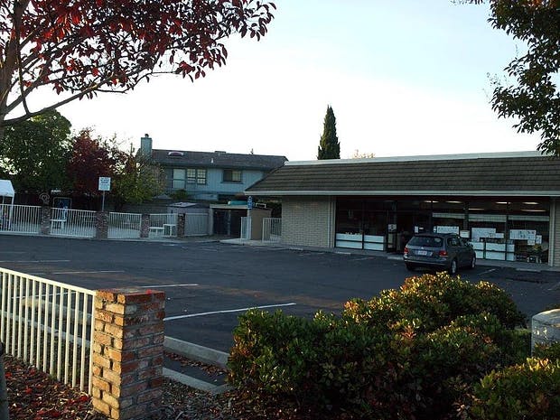 Building with a car parked in front, and another building in the background