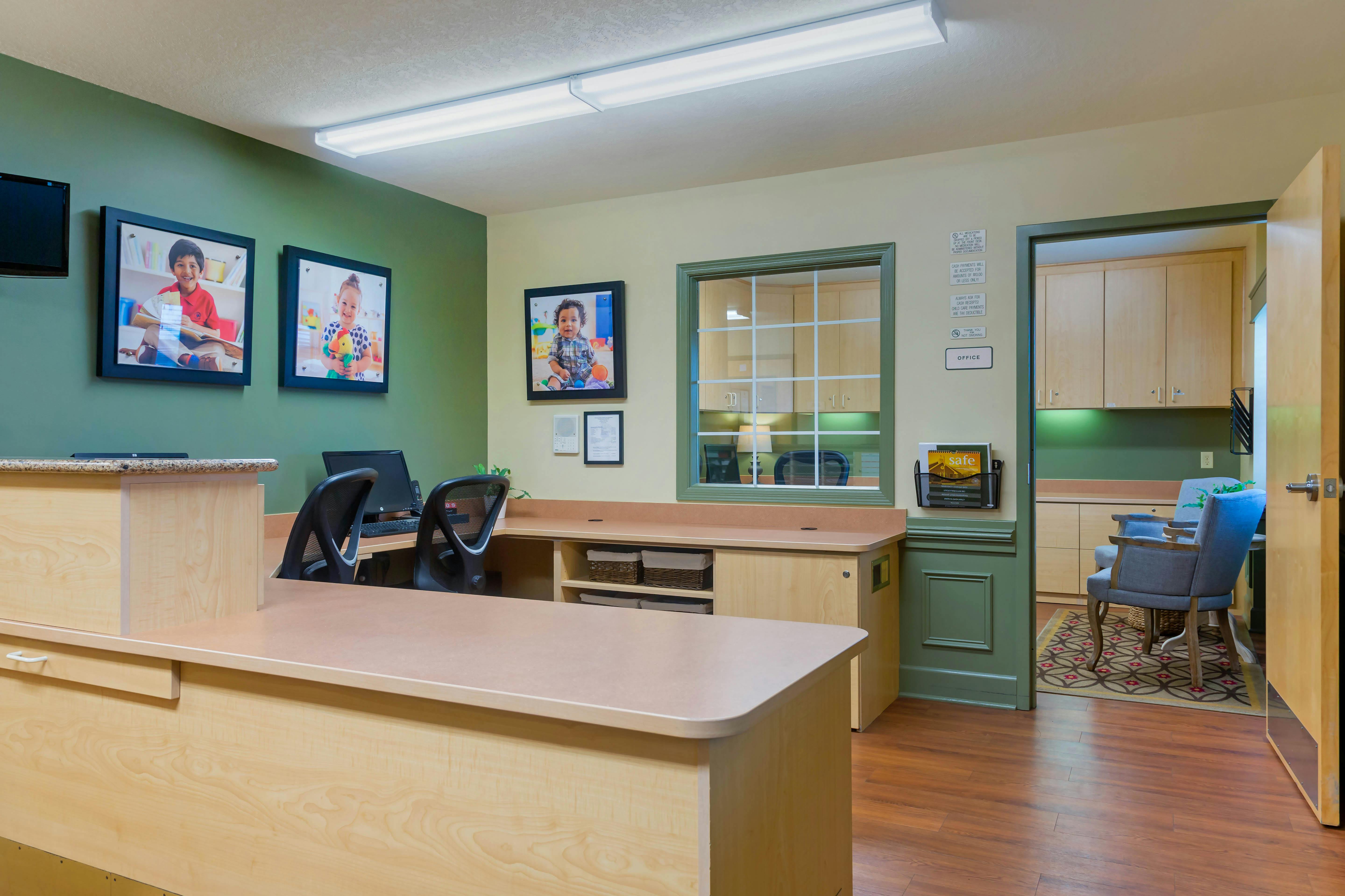 Reception desk with office door, window, and wall decorated with framed photos