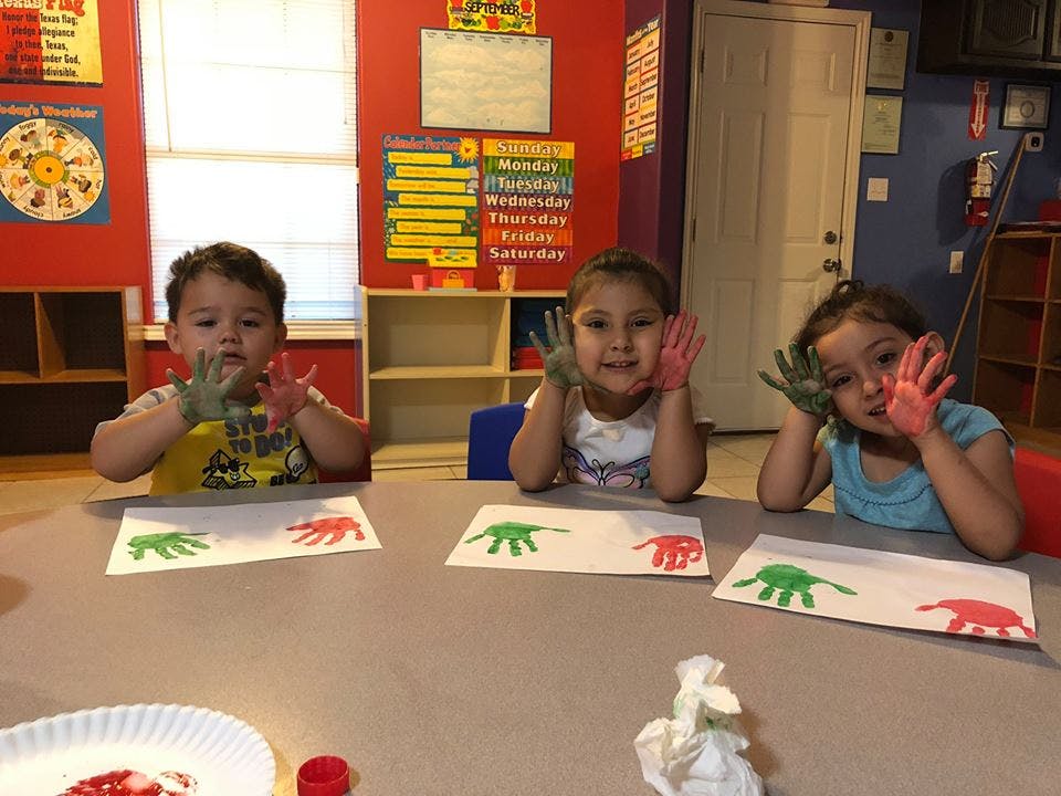 Three children with painted hands making handprint art