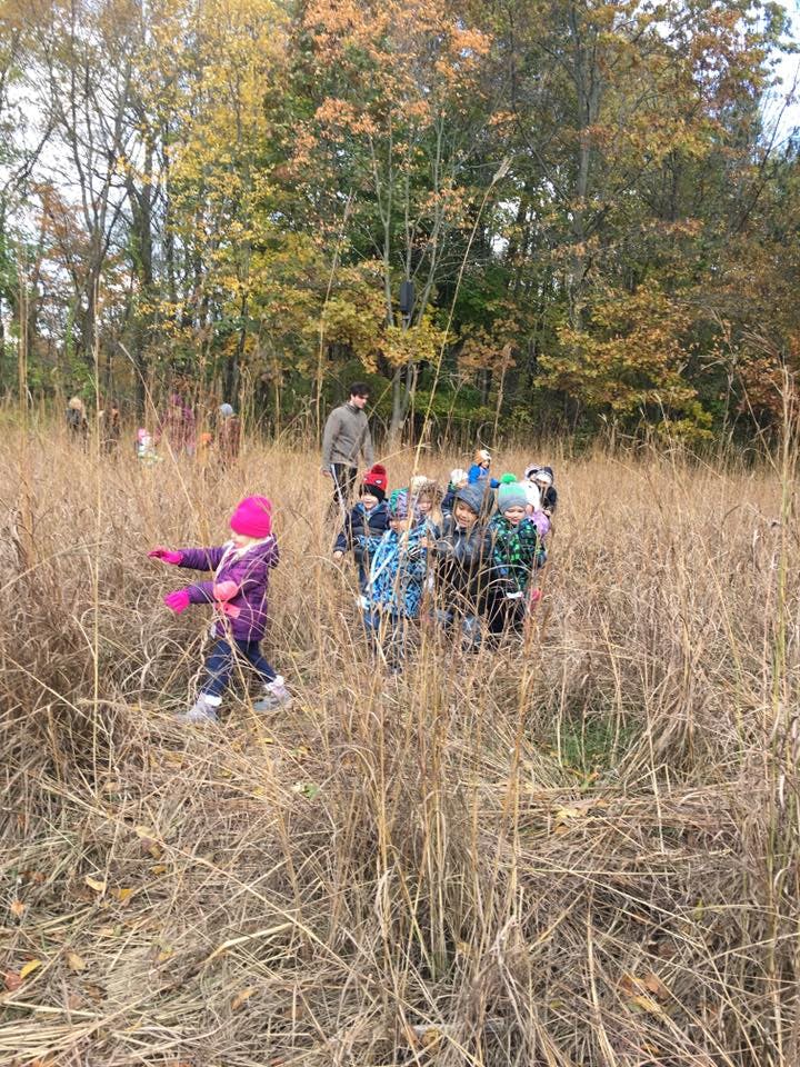 Adult and children walking through tall dry grass