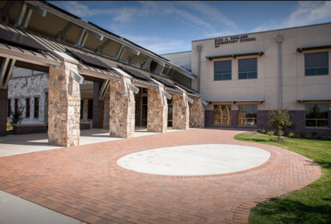Exterior of a building with stone columns and a brick walkway