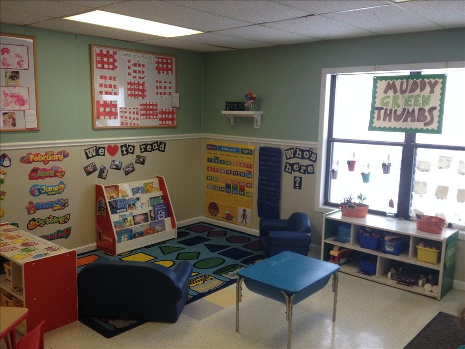 children's classroom with small tables, chairs, a bookshelf, and wall decorations