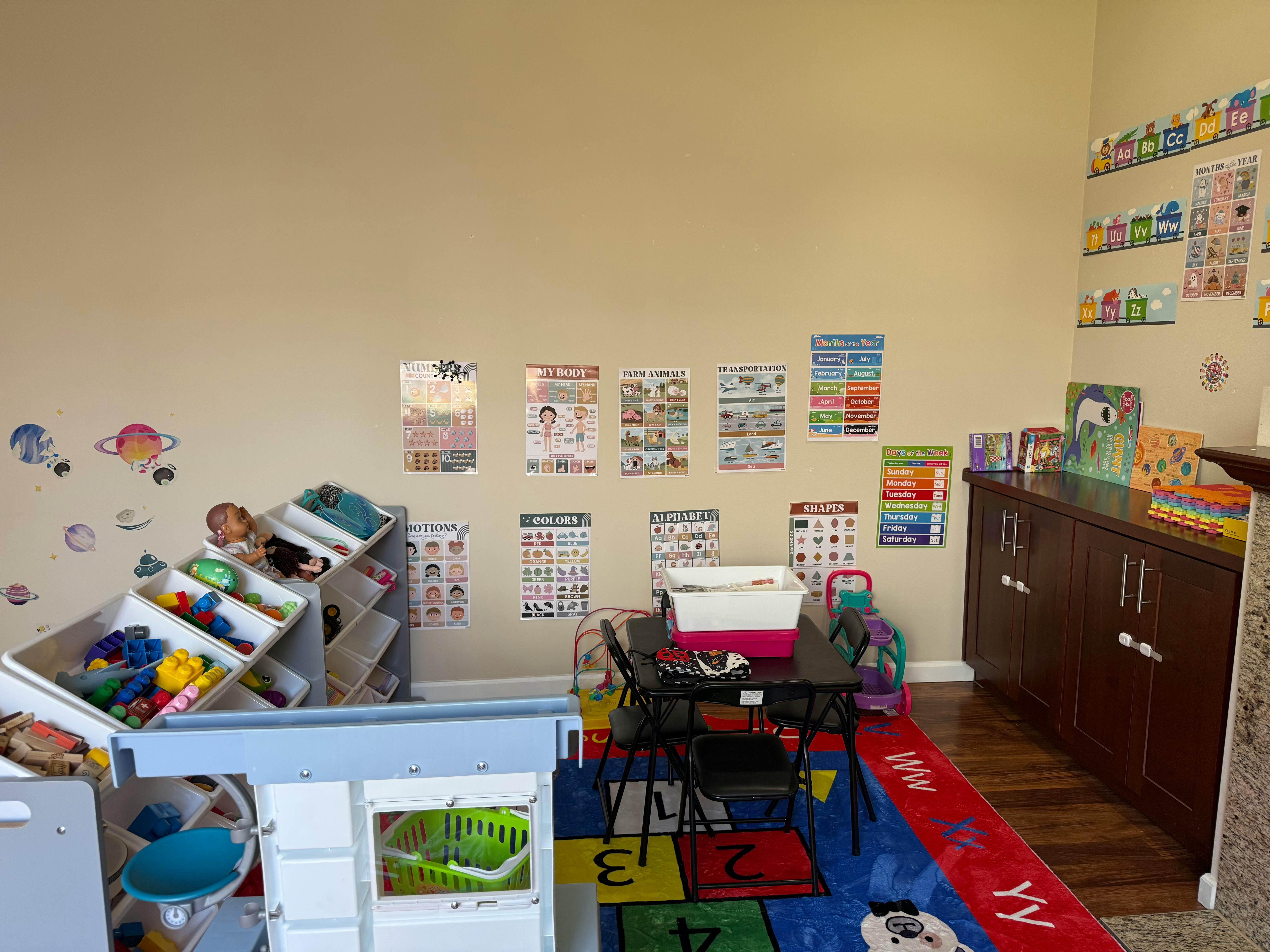 Classroom with educational posters, toy storage, and small table with chairs
