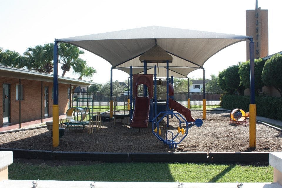 Playground with slides and climbing structures under a shade canopy