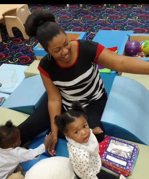 Person playing with two children in a play area
