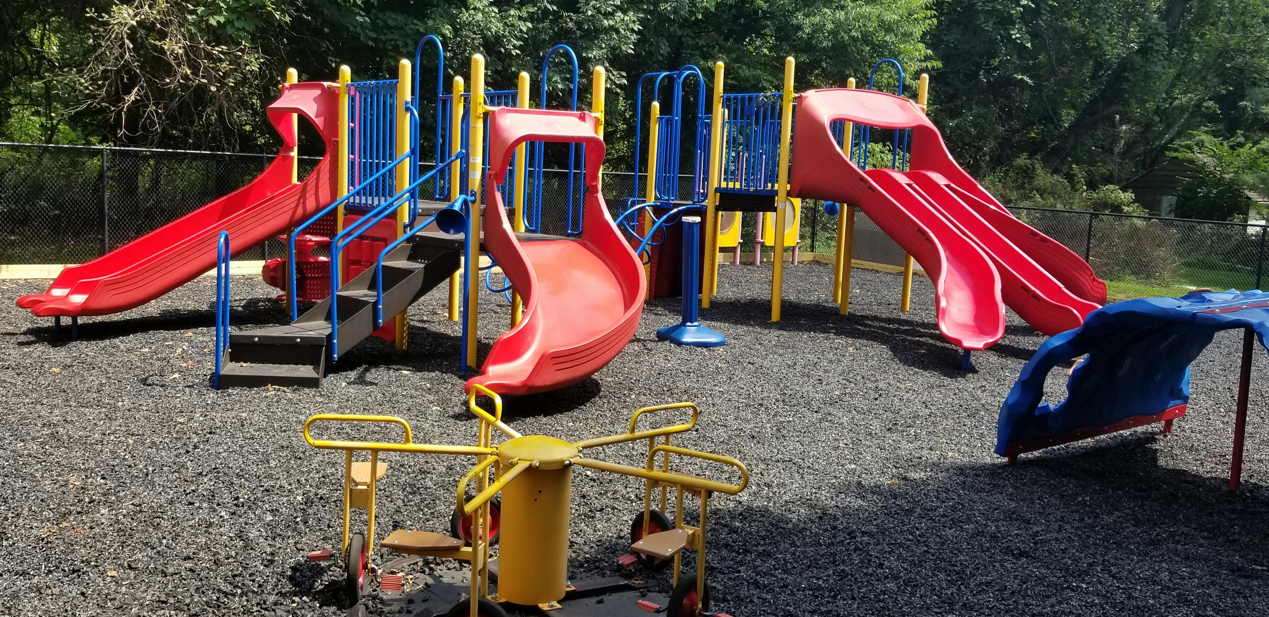 Playground with red slides and yellow and blue climbing structures