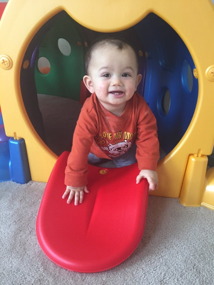 Child on a red slide coming out of a yellow play structure
