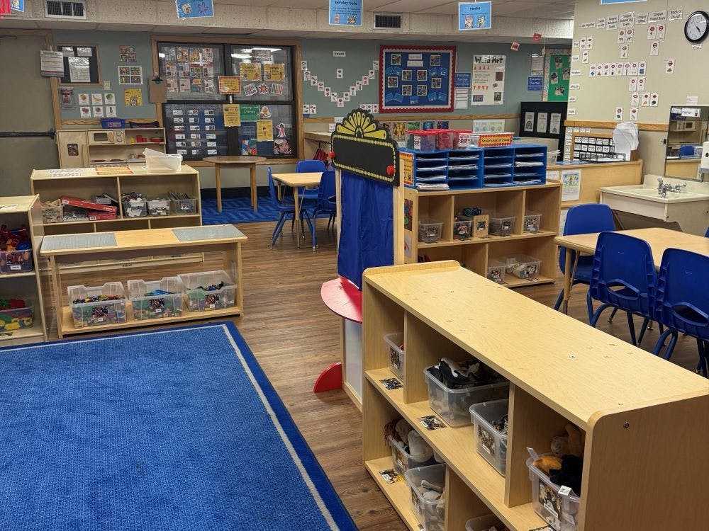 Classroom with shelves of toys, tables, and blue chairs