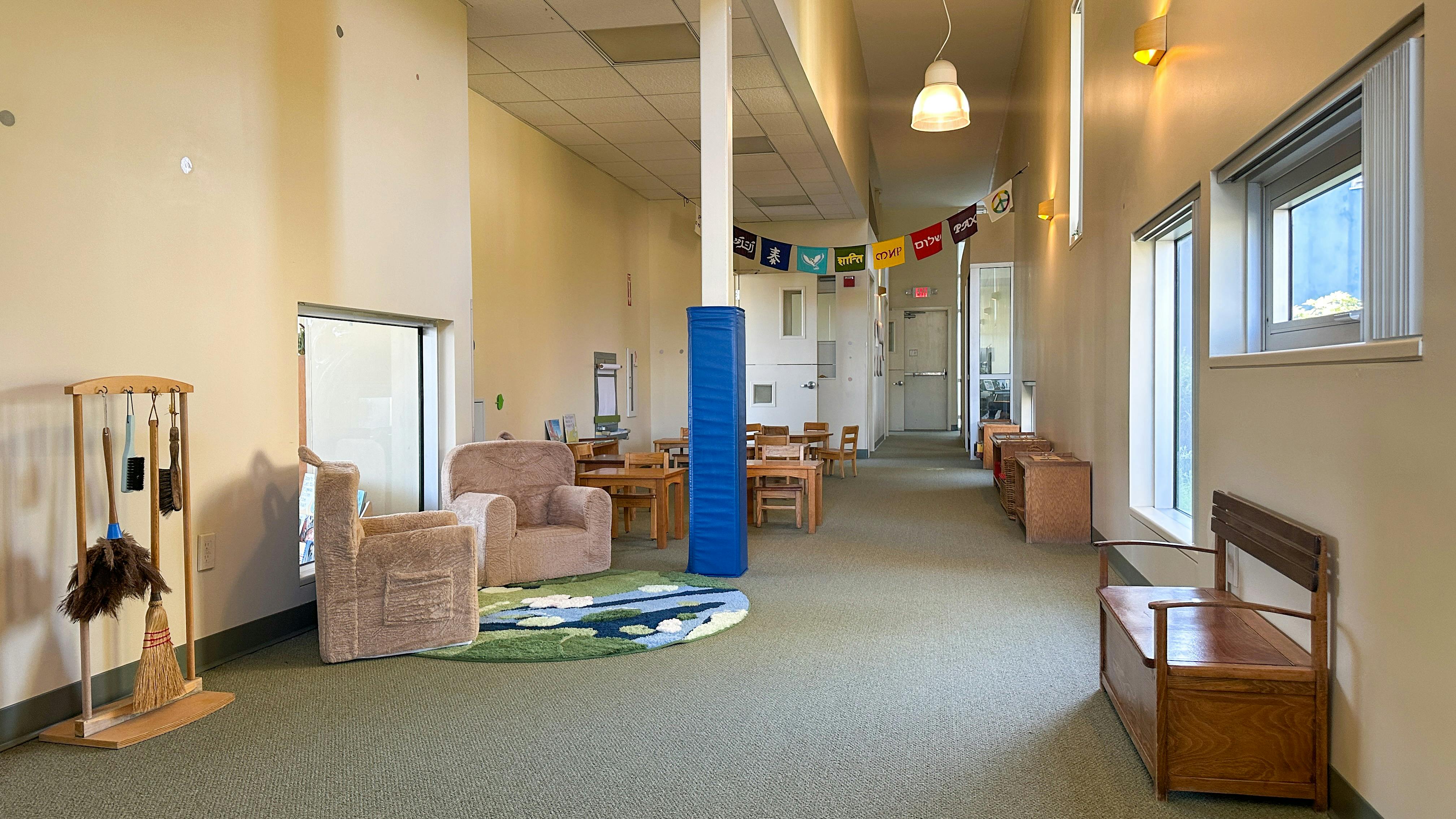 Classroom interior with small chairs and tables, child-sized armchairs, and a peace banner
