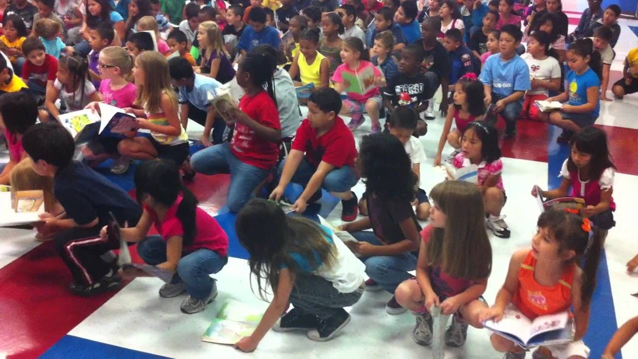 Many children sitting on the floor reading books