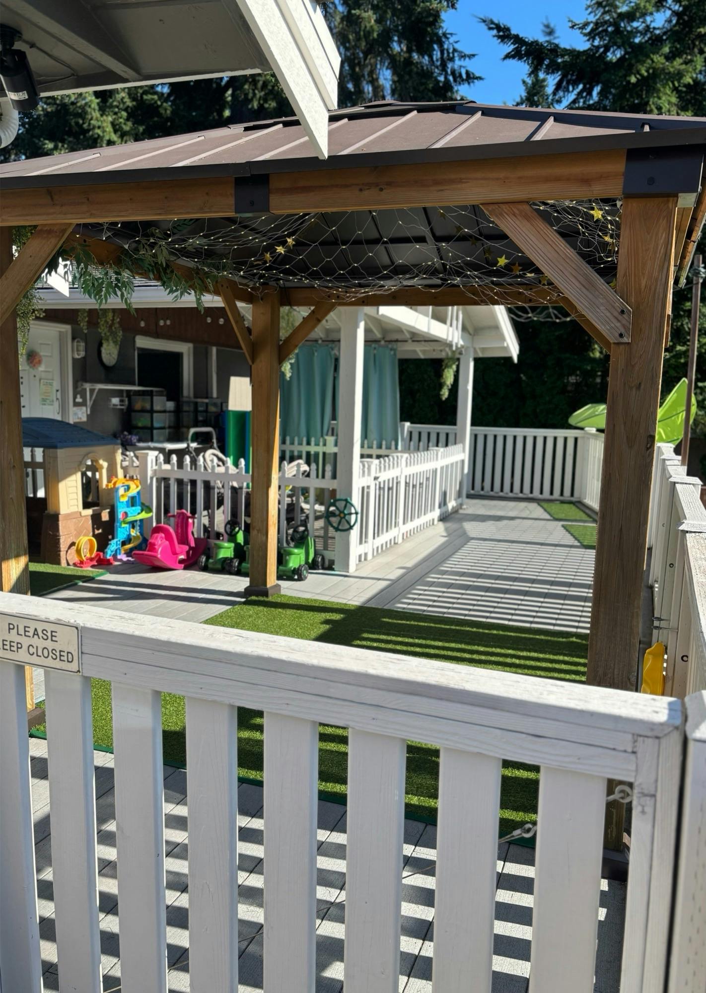 Outdoor play area with artificial turf, toys, and a wooden pergola