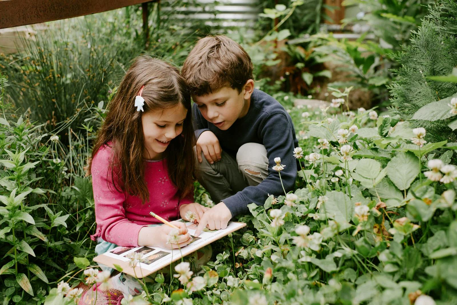 Two children observing and drawing outdoors