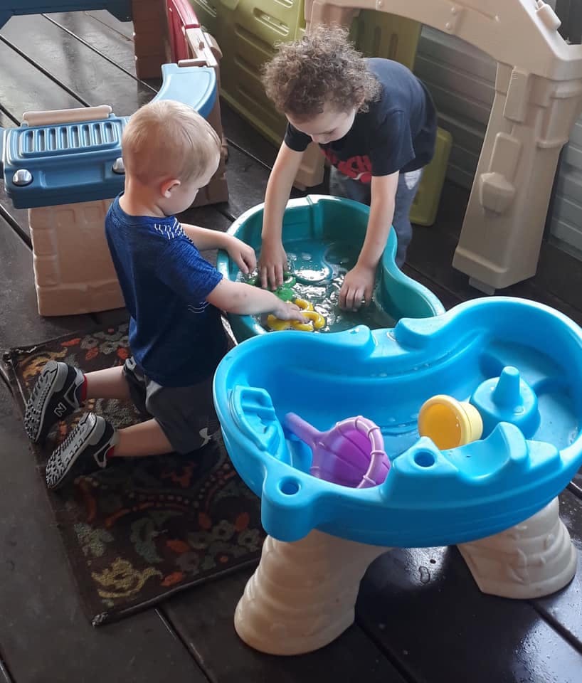 Two children playing with a water table