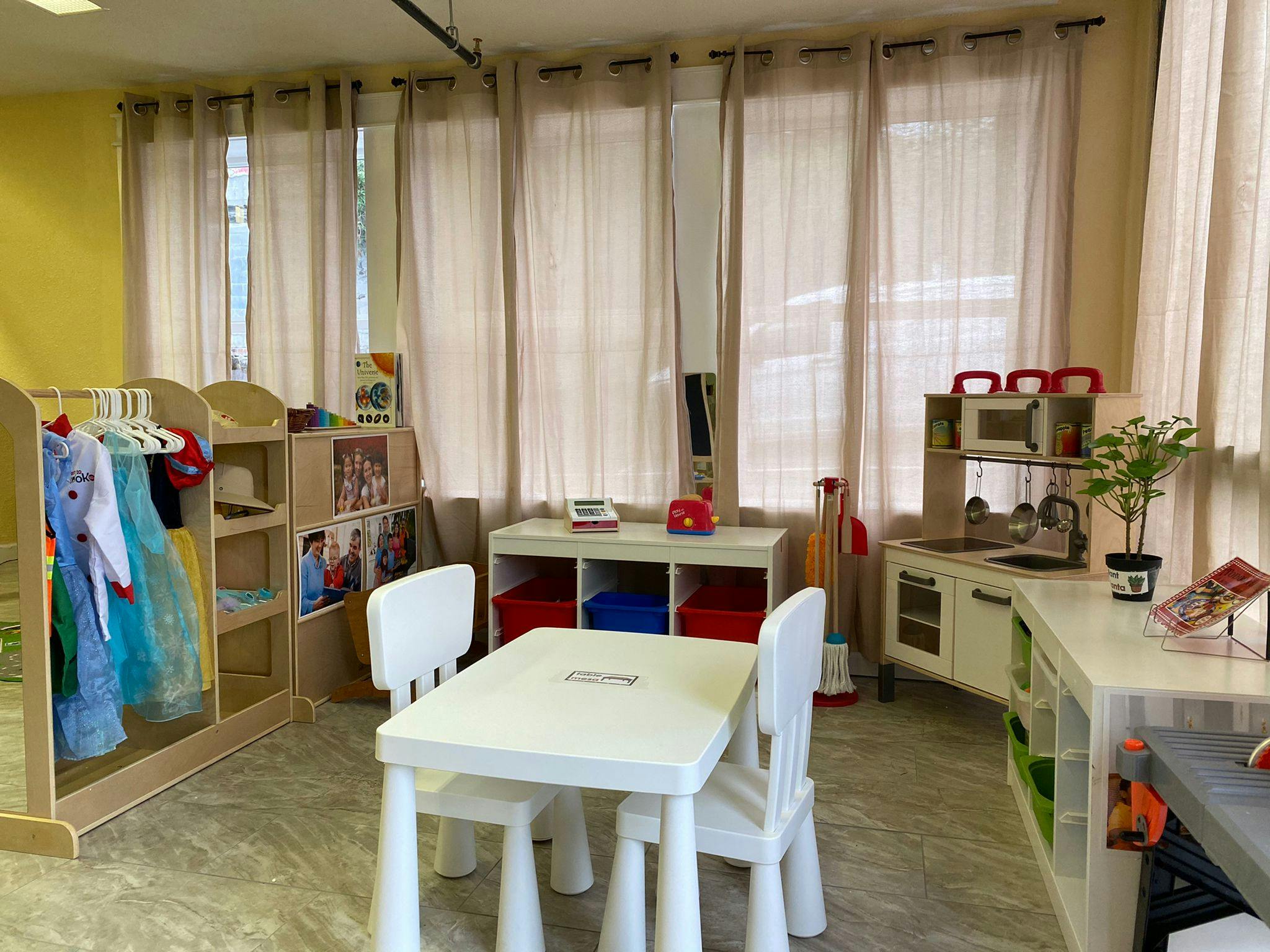 Children's classroom with dress-up clothes, play kitchen, and small table with chairs