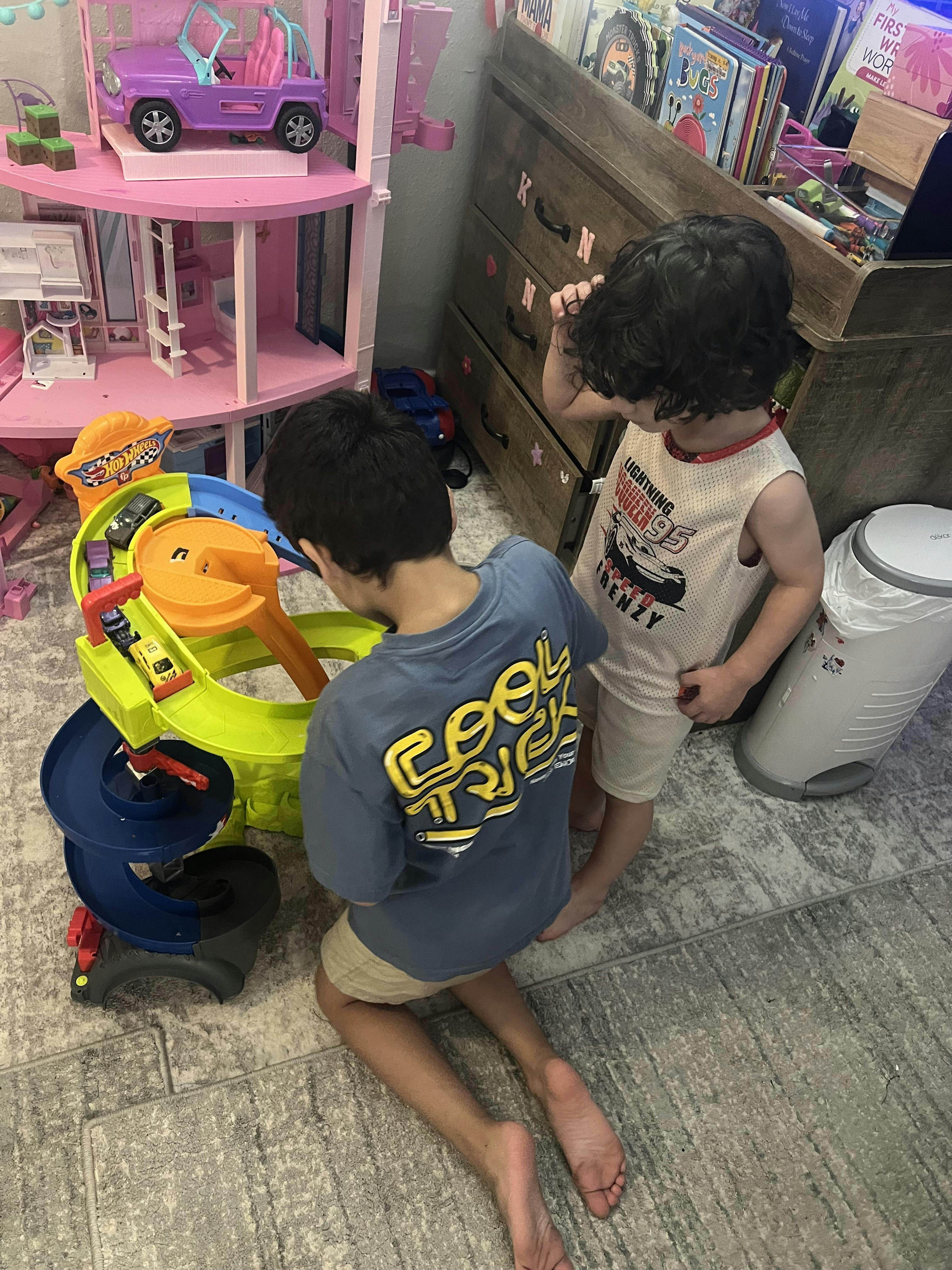 Two children playing with toy race tracks in a room