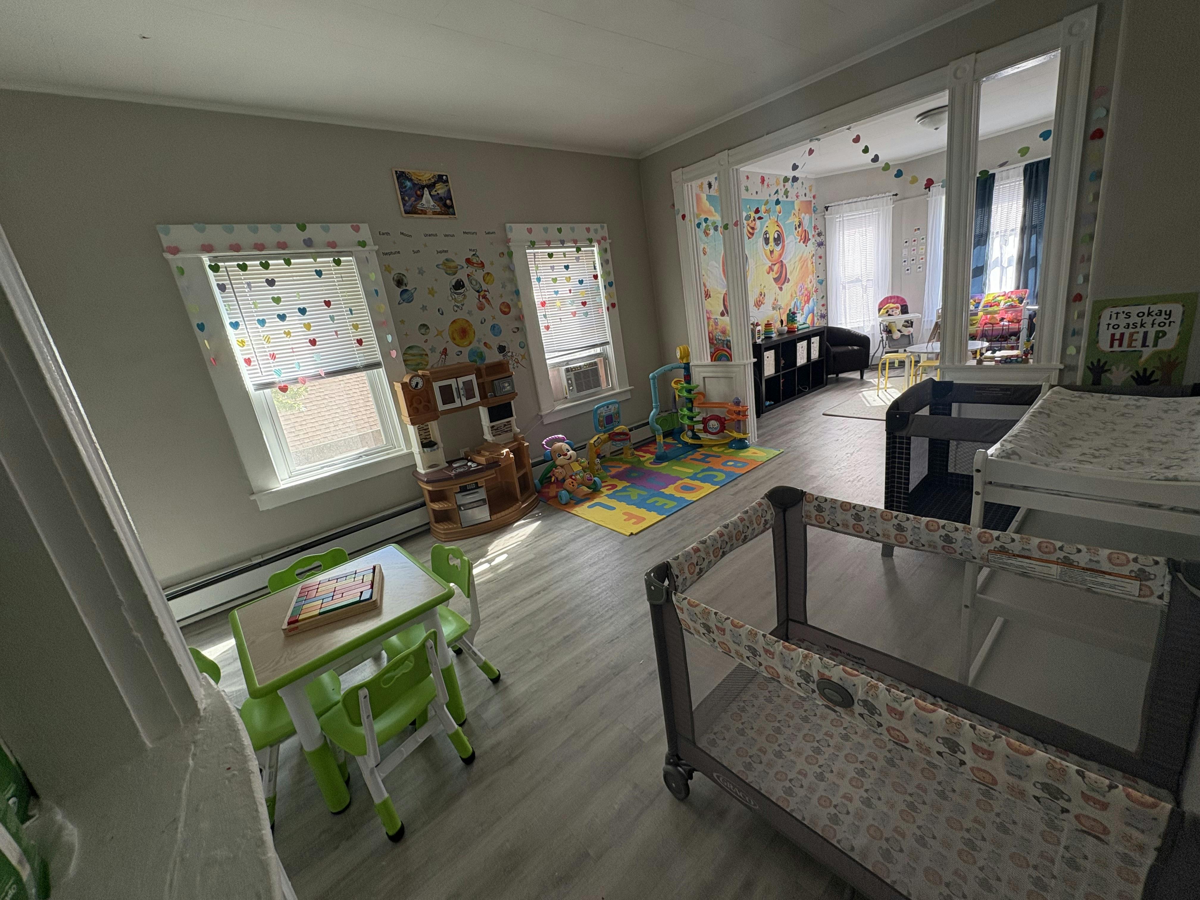 Playroom with small table and chairs, play mat, and cribs