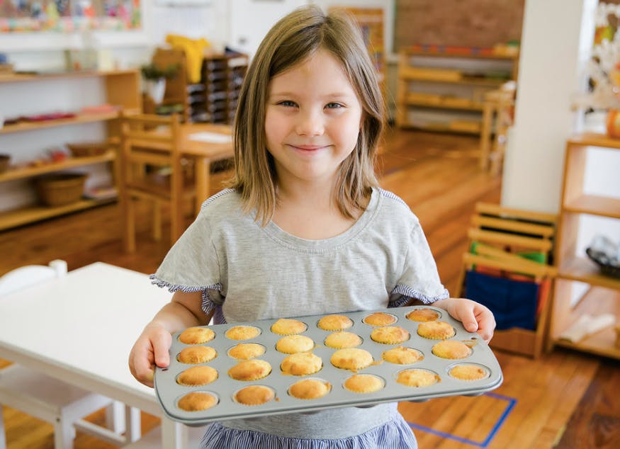 Child holding a muffin tin with baked goods
