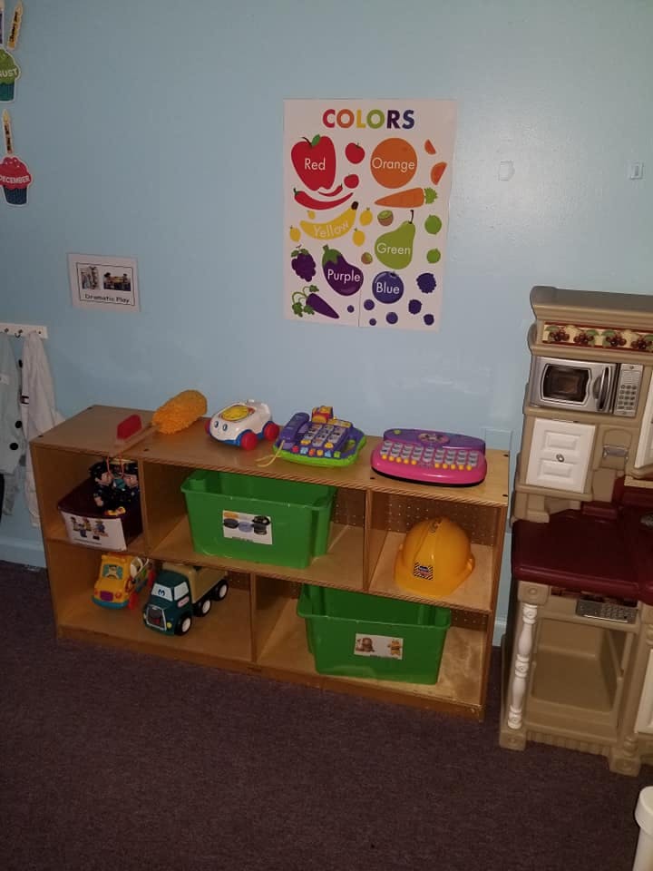 Playroom with a toy shelf, play kitchen, and a colors chart on the wall