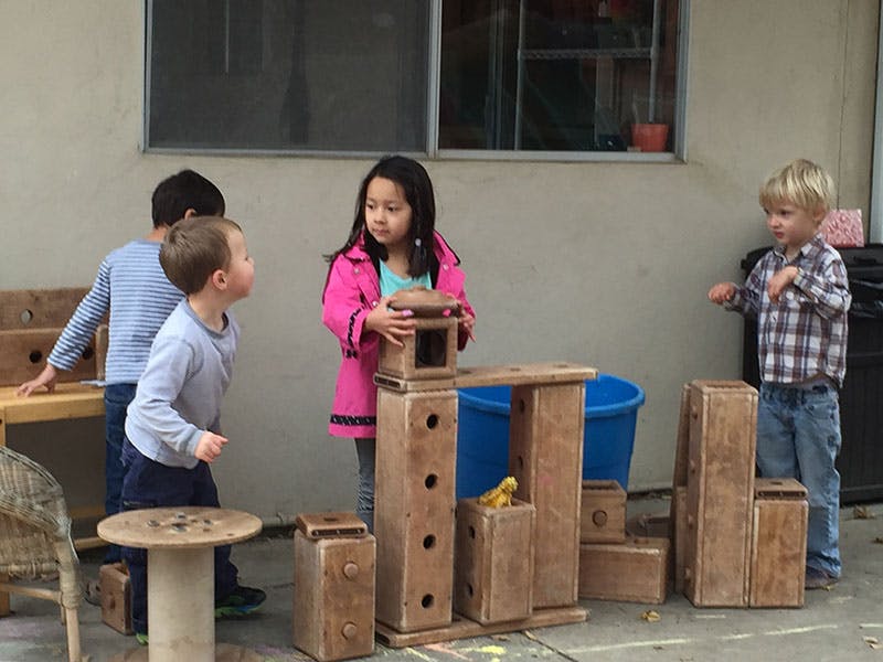Children playing with wooden blocks outdoors