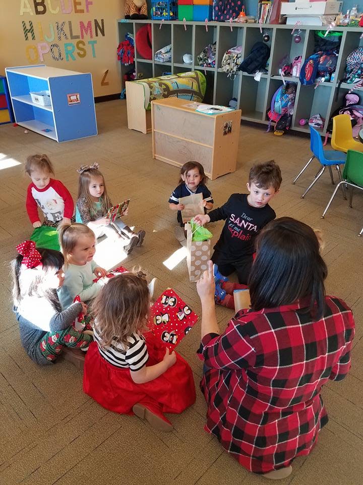 Adult and children sitting on the floor in a classroom with gifts