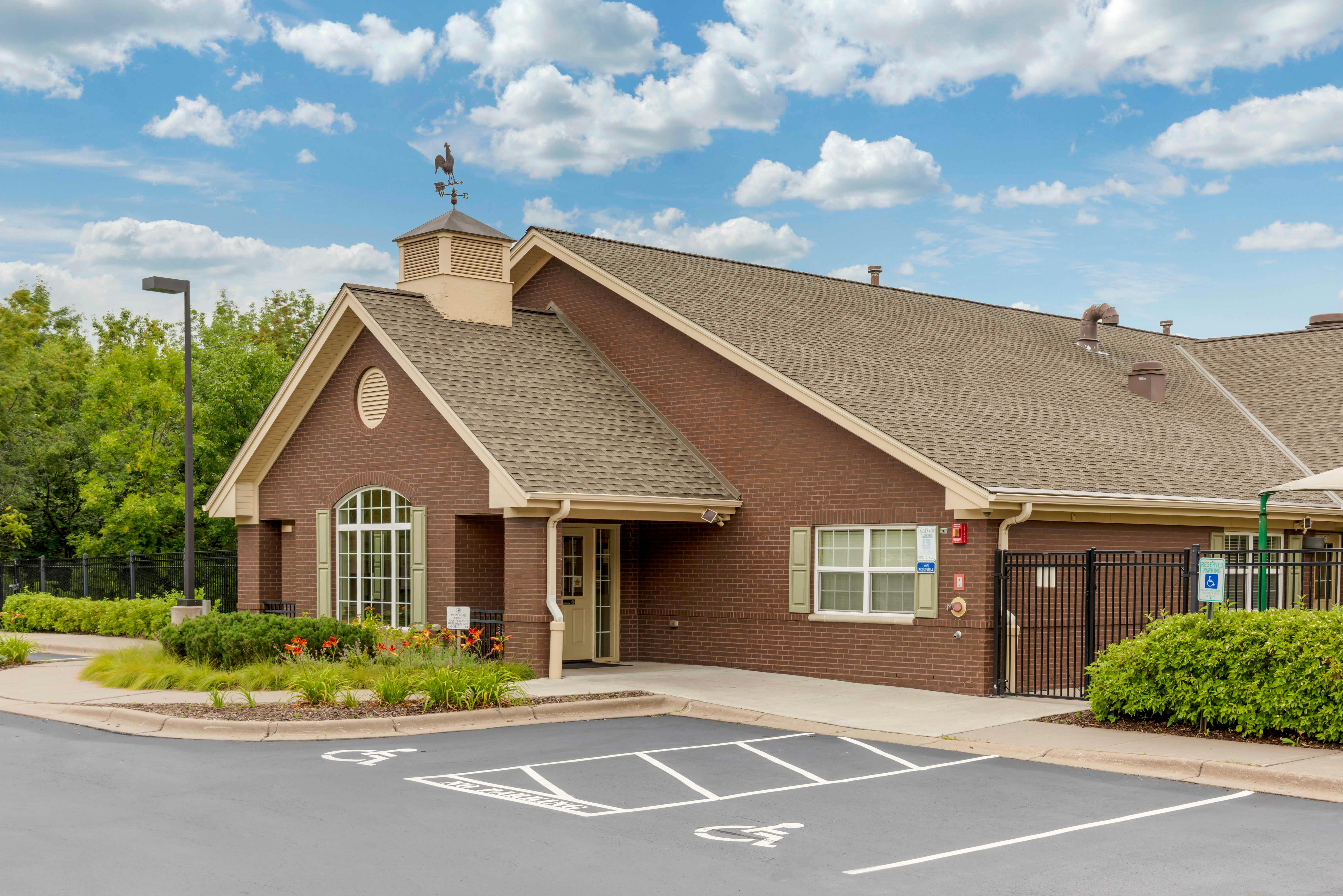 Brick building with a weather vane on the roof and an accessible parking lot