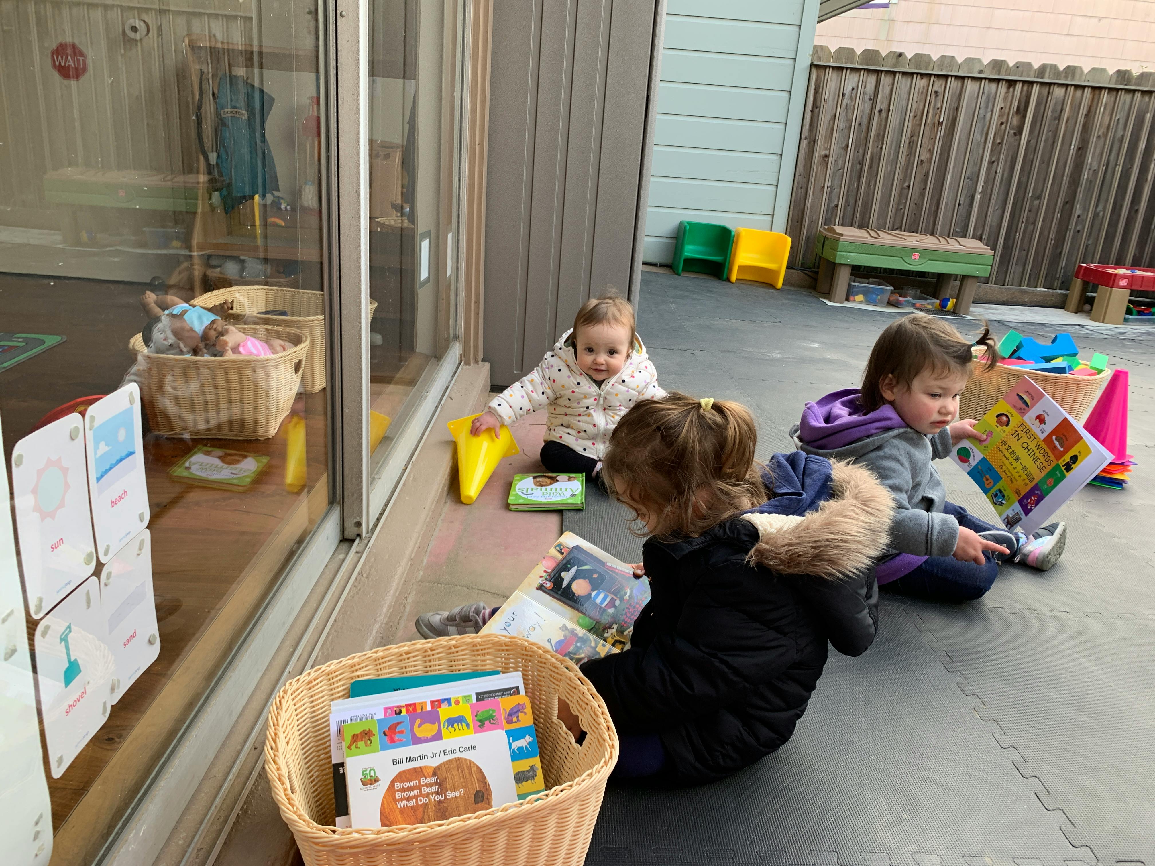 Three children sitting on the ground reading books