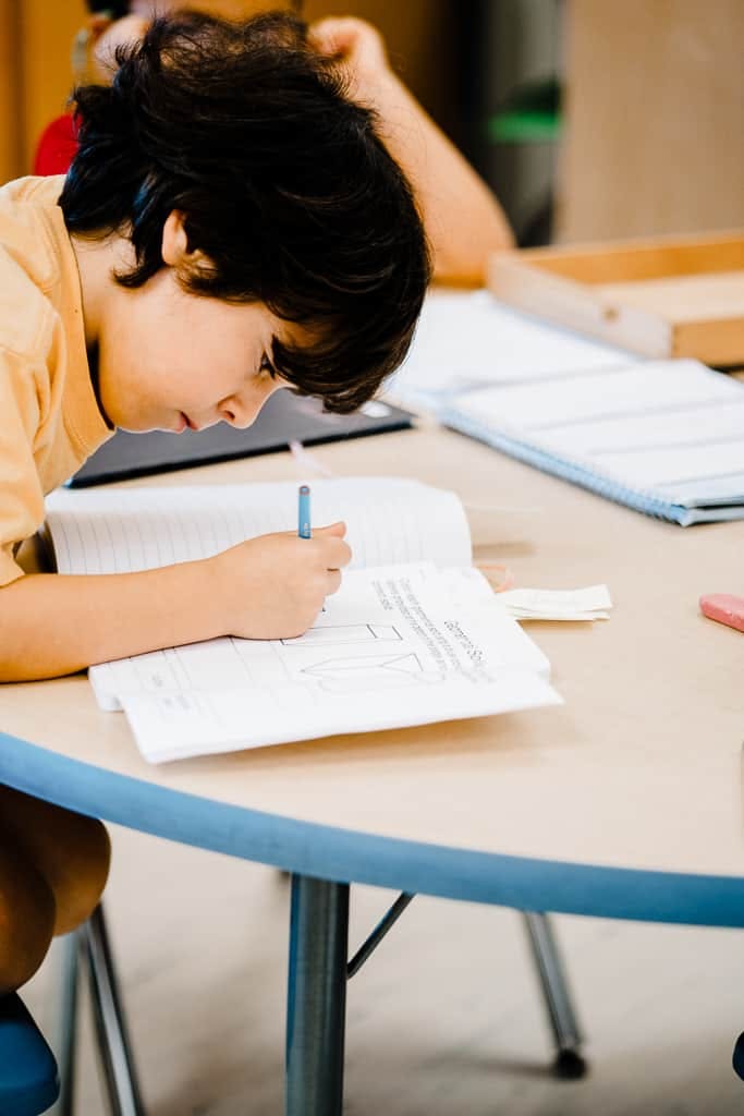 Child writing in a notebook at a table