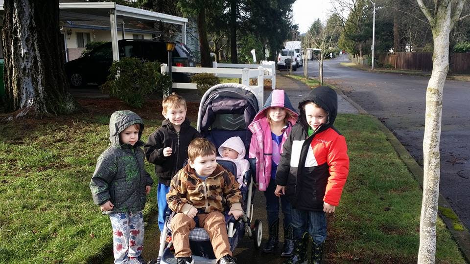 Five children and a baby in a stroller on a sidewalk