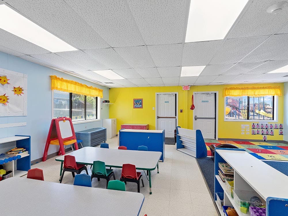 Colorful empty classroom with small tables and chairs, and an exit sign