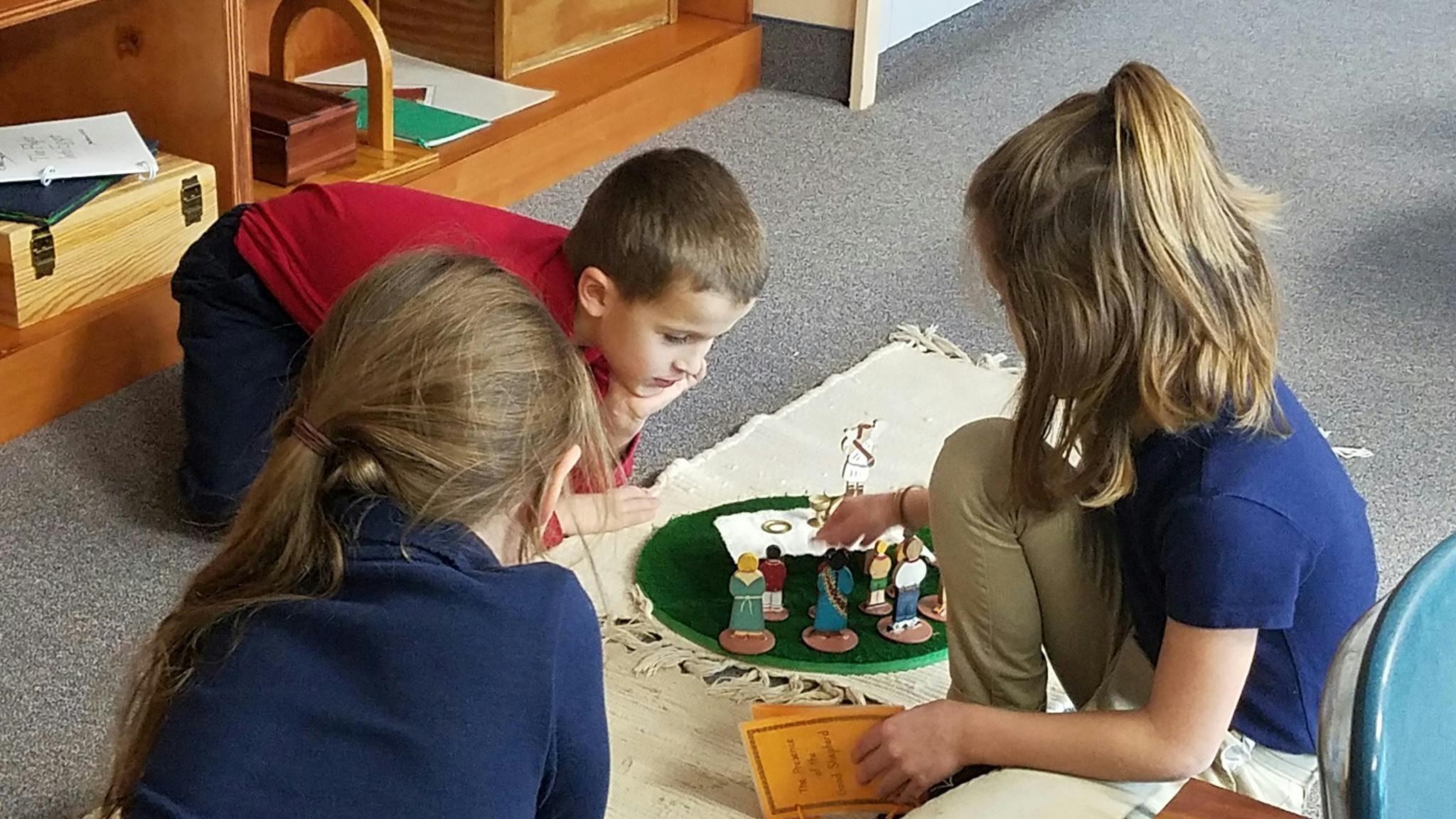 Three children playing with figurines on a mat
