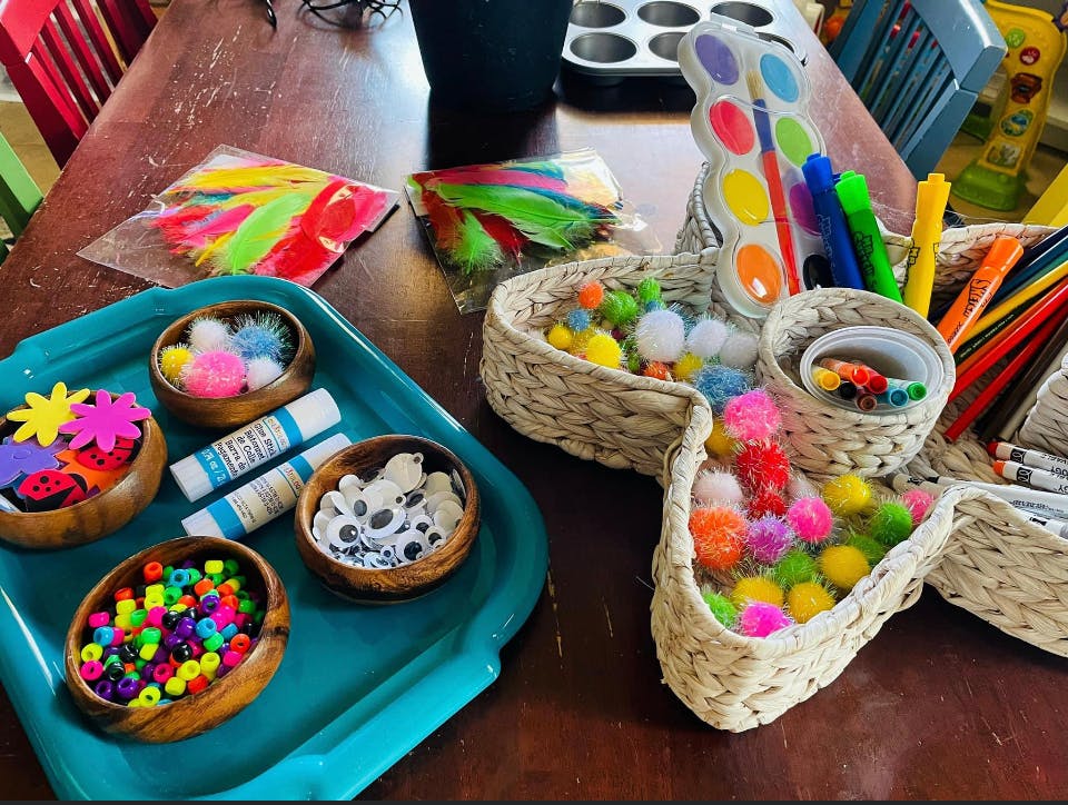 Craft supplies including beads, googly eyes, pom-poms, feathers, and paint