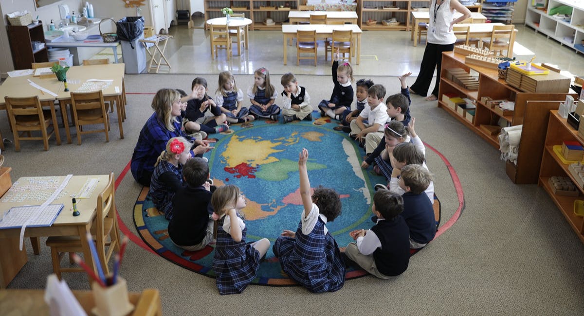 Children and an adult sitting in a circle on a rug in a classroom