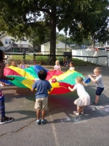 Children playing with a colorful parachute outdoors