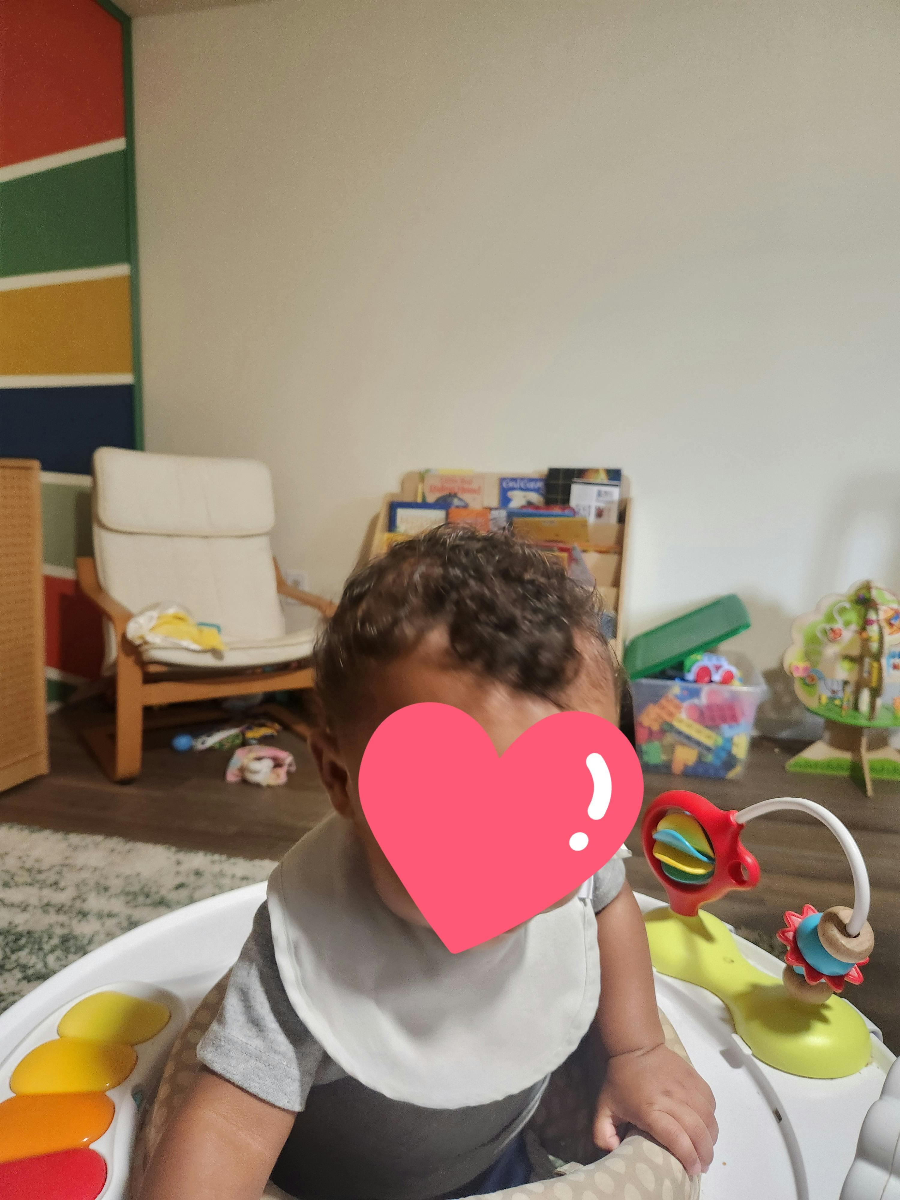 Baby wearing a bib in a baby bouncer with toys