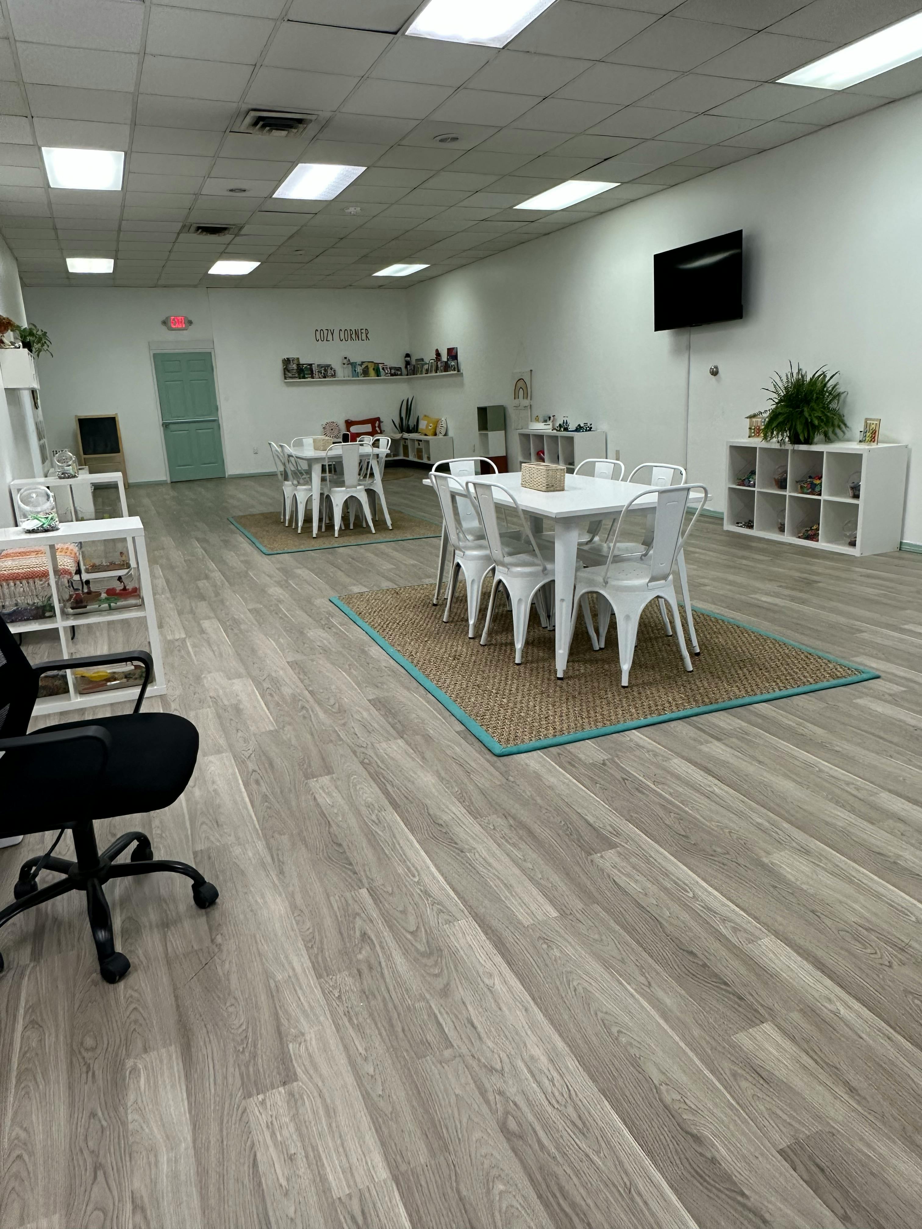 Room with multiple tables and chairs, a television, and shelves
