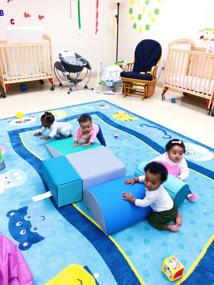 Four babies crawling and playing on soft blocks in a nursery