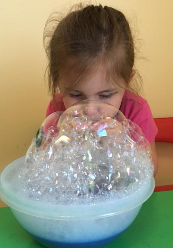 Child blowing bubbles into a bowl