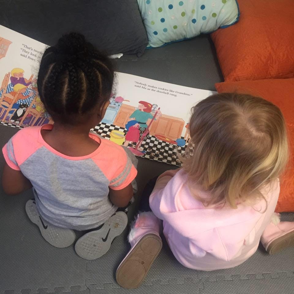 Two children sitting on the floor looking at an open book