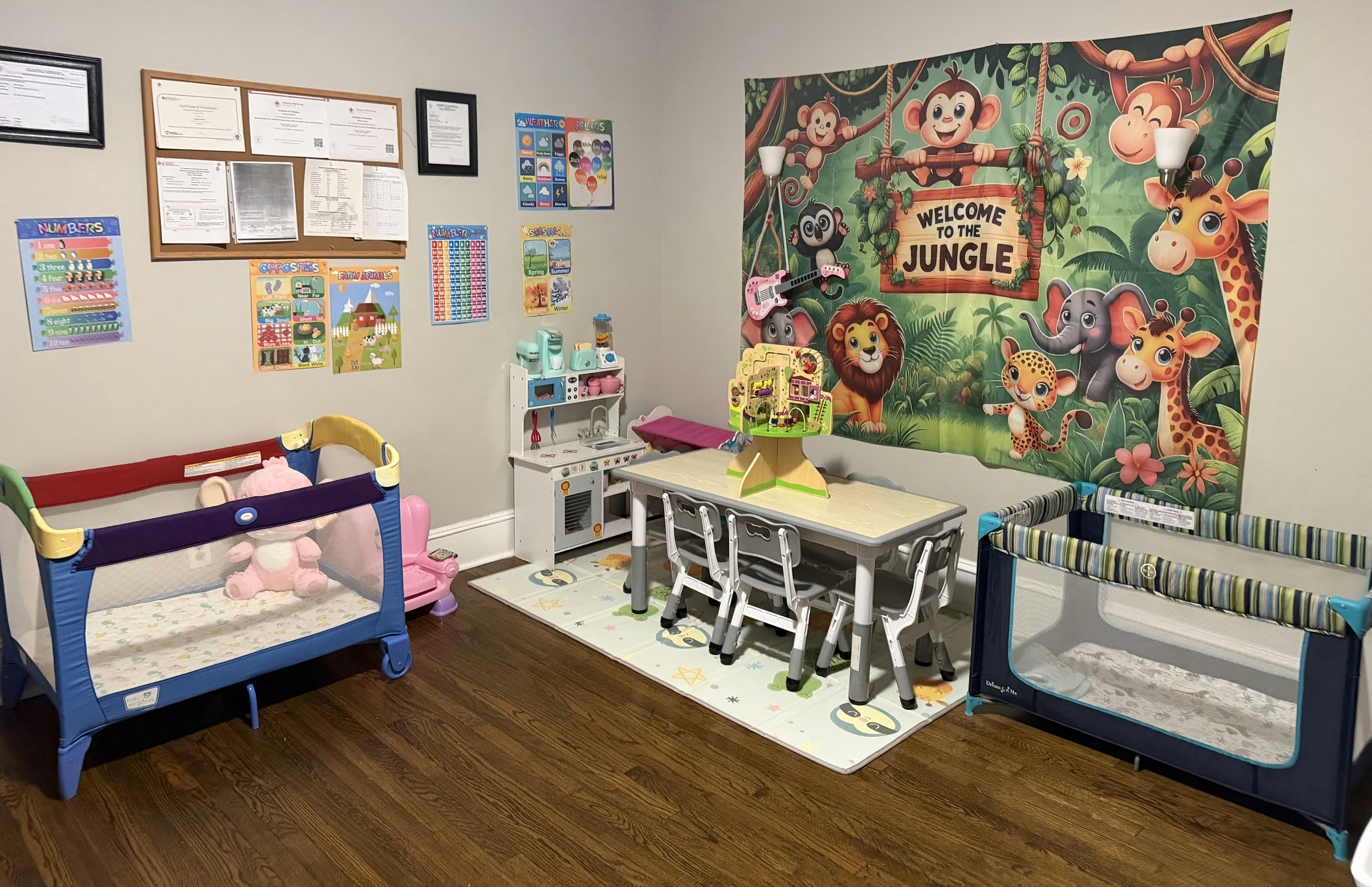 Childcare room with play equipment, small table, and jungle-themed wall decor