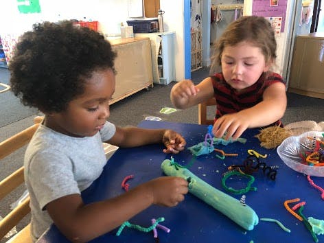 Two children playing with craft materials at a table