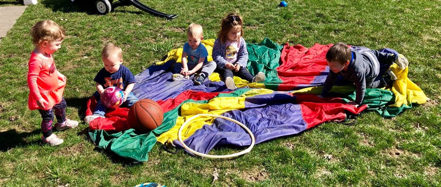 Children playing on a colorful parachute on grass