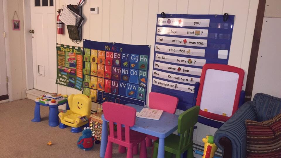 Children's play area with small table and chairs, alphabet chart, and word chart